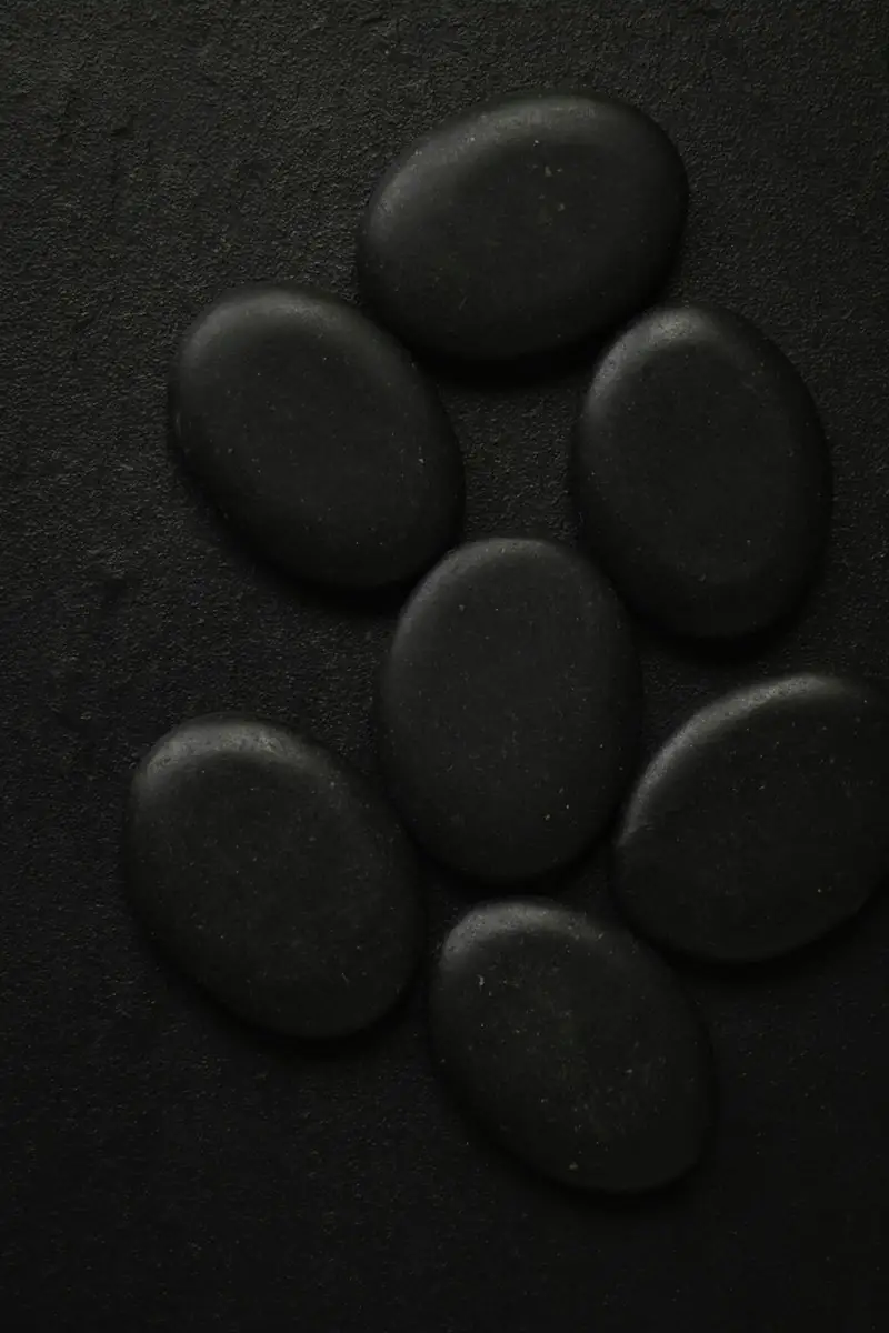 Sieben glatte schwarze Steine auf dunklem Grund