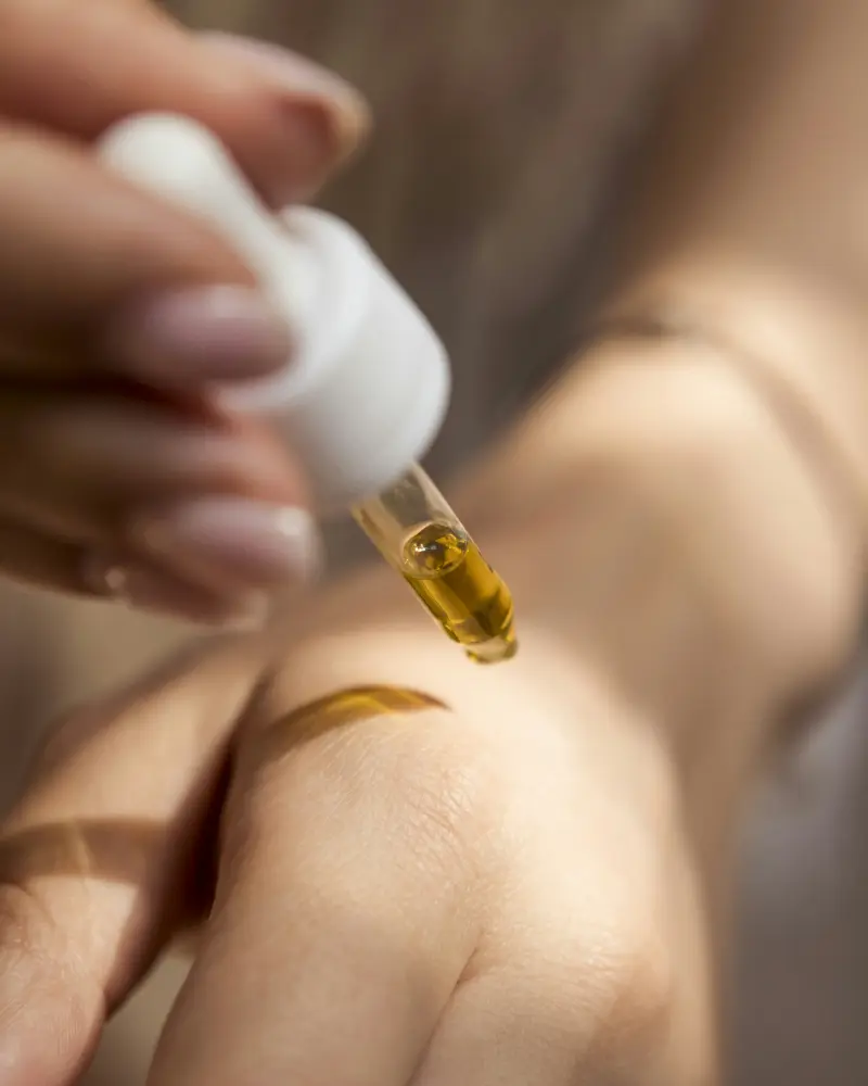 Ein Tropfen Serum aus der Pipette auf dem Handrücken