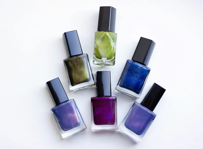 Fünf Nagellackfläschchen in Grün, Blau und Violett