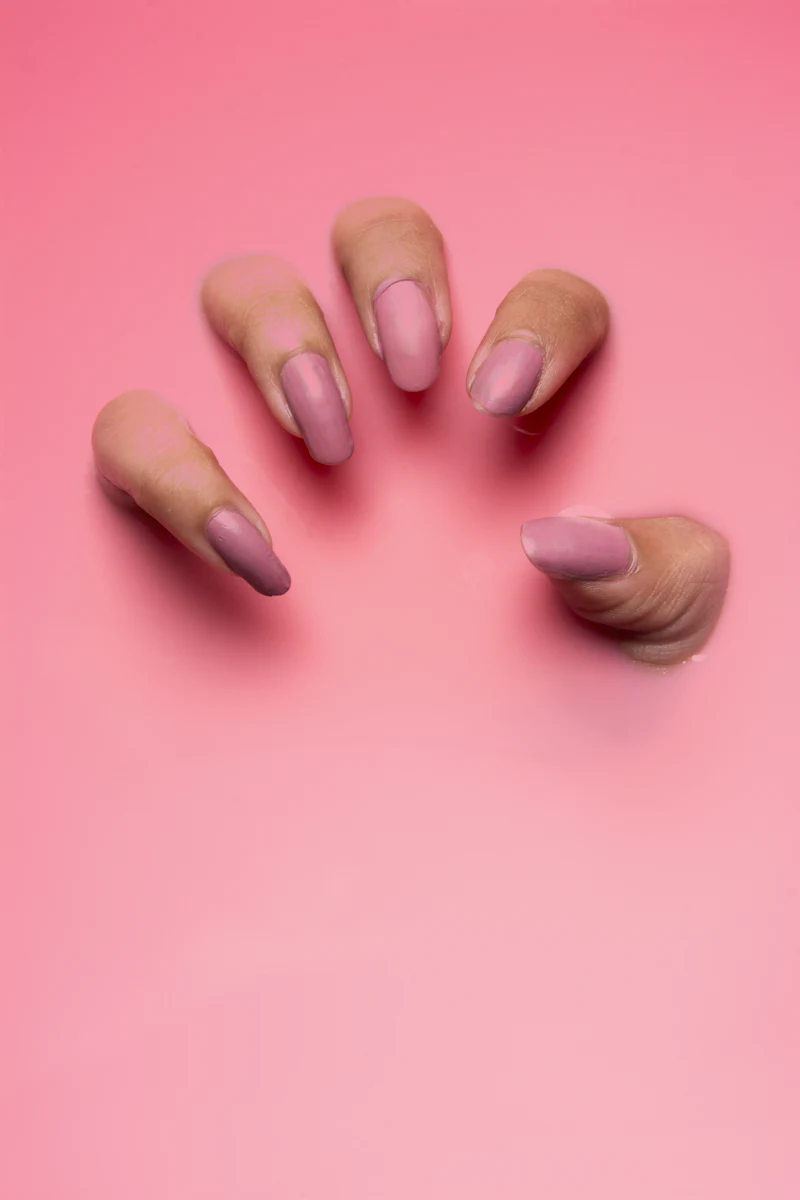 Hand mit rosa lackierten Nägeln auf rosa Hintergrund