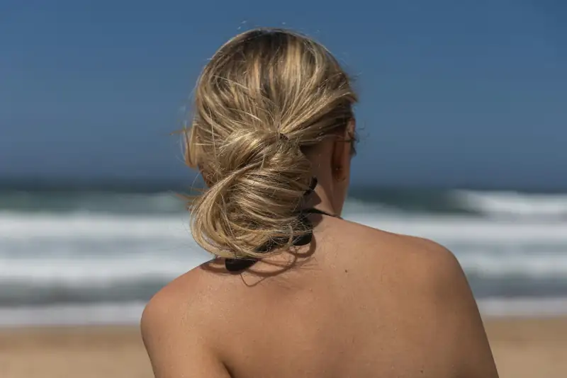 Locker hochgesteckter Knoten in Blond vor dem Meer