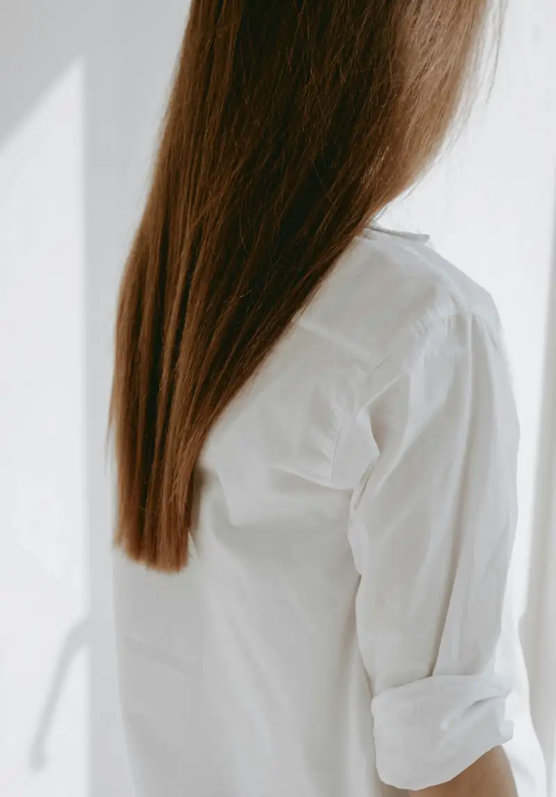 Langes, glattes braunes Haar über einer weißen Bluse