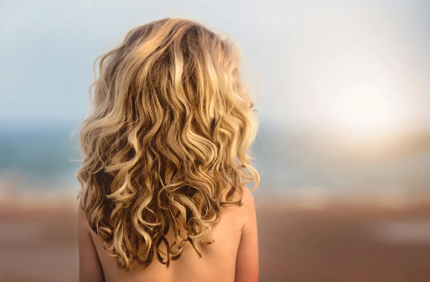 Lange, honigblonde Locken von hinten im warmen Abendlicht