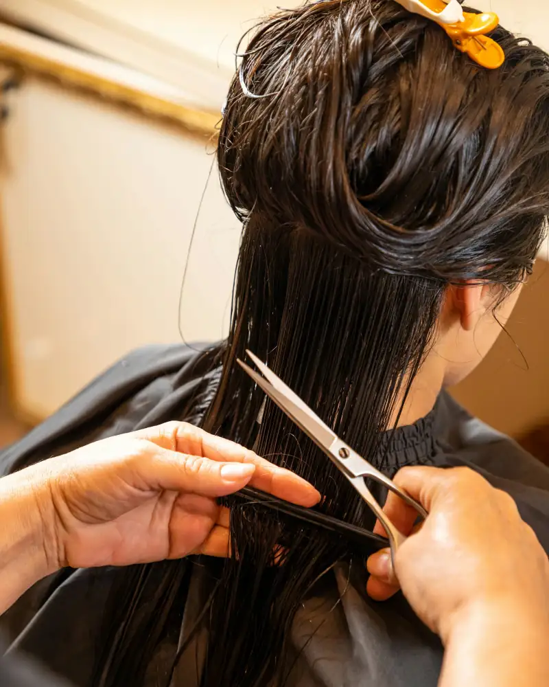 Eine Friseurin schneidet nasses, dunkles Haar mit der Schere