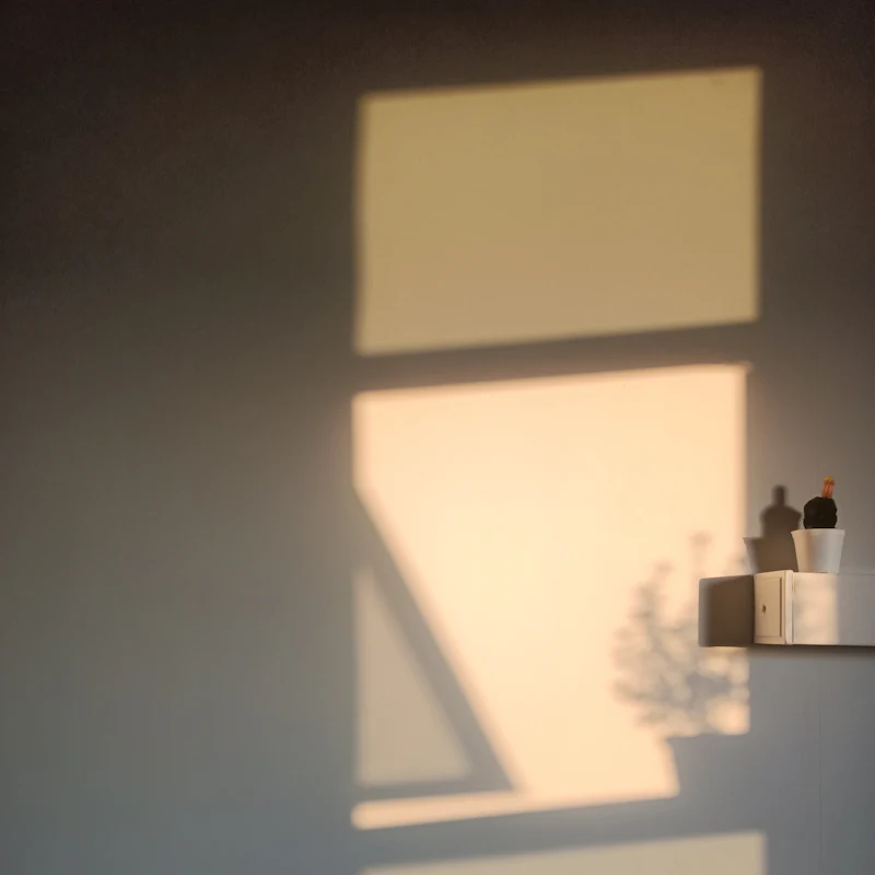 Abendlicht fällt durch ein Fenster auf eine helle Wand